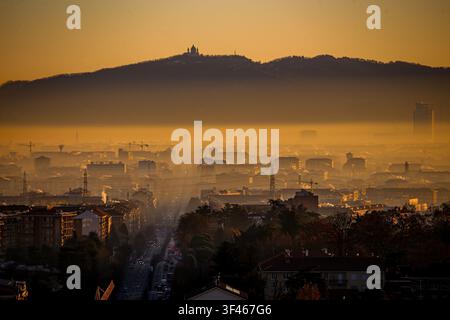 Vue aérienne de la basilique de Superga sur la colline surplombant la ville de Turin au coucher du soleil, avec une épaisse couche de smog atmosphérique recouvrant l'urbain Banque D'Images