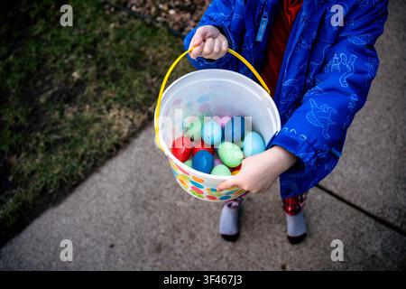 Enfant tenant un panier rempli d'œufs de Pâques Banque D'Images