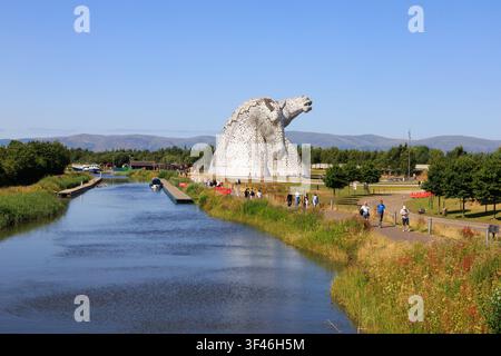 Visiteurs aux Kelpies, les sculptures emblématiques de têtes de cheval de 30 mètres de haut à The Helix à Falkirk, en Écosse, par une journée d'été claire. Banque D'Images