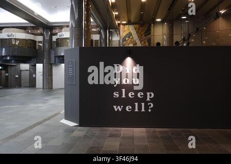 Un mur d'affichage noir avec le texte « Avez-vous bien dormi ? » éclairé par un projecteur dans le hall moderne d'un bâtiment au Japon. Banque D'Images