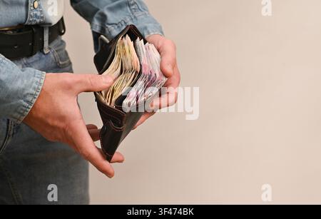 Le portefeuille illustre la gestion physique de l'argent, le budget ou un gain en espèces inattendu. Hryvnia ukrainienne. Concept financier illustré par une main tenant un tas d'argent Banque D'Images