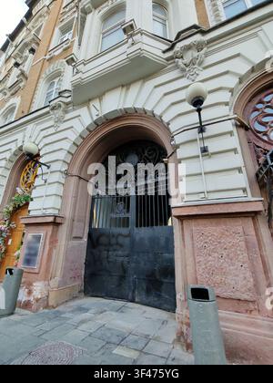 Une grande porte en fer forgé sous une arche en pierre ornée de sculptures détaillées et de colonnes. Cette image capture des thèmes de l'histoire urbaine et Banque D'Images