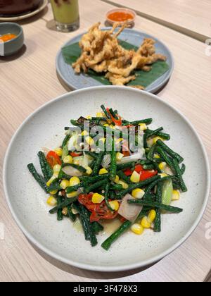 Salade de légumes mélangés fraîche avec haricots verts, maïs, poivrons et oignons servis avec une tempura croustillante dans un restaurant japonais. Banque D'Images