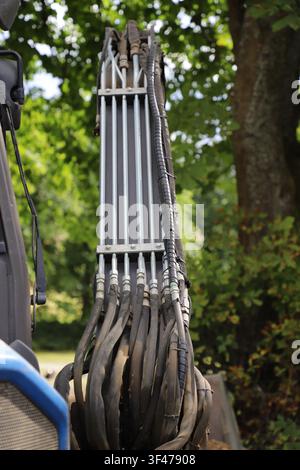 Grossissement des tuyaux hydrauliques et des pipelines en acier sur la flèche d'une pelleteuse compacte. Système hydraulique haute pression alimentant les accessoires de la pelleteuse Banque D'Images