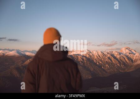 Person debout au-dessus des crêtes des montagnes pendant le coucher du soleil dans les Dolomites. Paysage alpin pittoresque avec des pics superposés et la lumière de l'heure dorée Banque D'Images