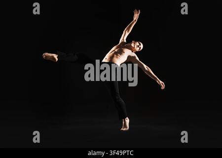 Danseur professionnel pratiquant des mouvements sur fond noir Banque D'Images