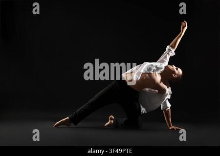 Danseur professionnel pratiquant des mouvements sur fond noir Banque D'Images