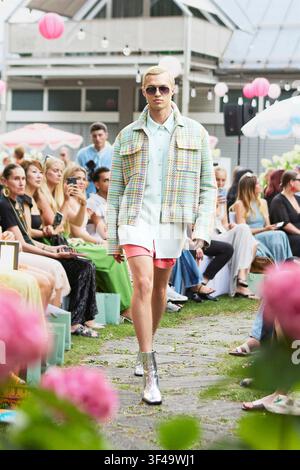 Munich, Allemagne, 16 juillet 2026. Un mannequin défile sur le podium vêtu d'une veste en tweed pastel, d'une chemise menthe clair, d'un short rose corail et d'une botte argentée métallique Banque D'Images