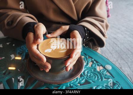 Person tenant une boisson chaude sur une table Banque D'Images