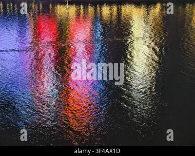 Réflexions de lumière colorées sur une surface d'eau ondulante Banque D'Images