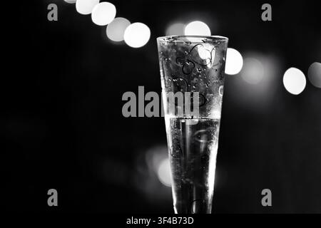 Flûte à champagne noir et blanc avec lumières bokeh festives sur fond sombre, concept de célébration élégant Banque D'Images