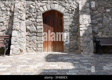 Mur de pierre ancien porte en bois arquée tendance cottagecore. Façade de château de vieille ville européenne restaurée avec balustrade en fer forgé et vintage Banque D'Images