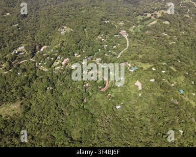 Vue aérienne de la réserve forestière nuageuse luxuriante de Monteverde avec un dense couvert vert, des routes sinueuses et des bâtiments dispersés nichés dans les montagnes de Mo Banque D'Images