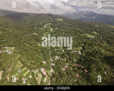 Vue aérienne de la réserve de forêt nuageuse de Monteverde avec un couvert végétal luxuriant, des routes sinueuses et des bâtiments dispersés nichés dans les montagnes de Monteverde Banque D'Images
