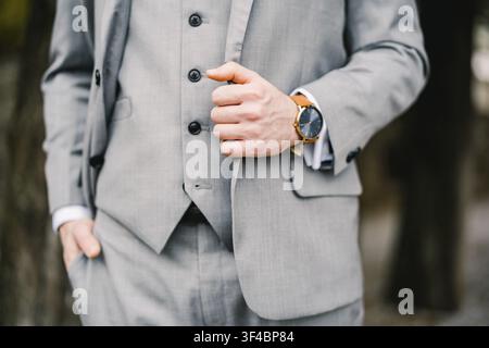 Homme en costume gris se tient une main dans la poche du pantalon et l'autre tenant le revers de sa veste. Visage coupé anonyme. Banque D'Images