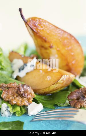 Salade aux poires caramélisées, fromage bleu et noix sur une assiette bleue Banque D'Images