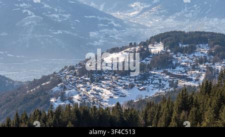 Village alpin avec des maisons nichées dans des montagnes enneigées Banque D'Images