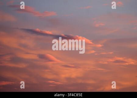 Beau ciel pastel au coucher du soleil avec des nuages doux roses, orange et violets créant un fond naturel paisible. Banque D'Images