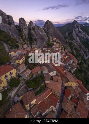 Vue aérienne du village historique de Castelmezzano niché parmi les pics rocheux dramatiques des montagnes Dolomiti Lucane au coucher du soleil à Castelmezzano Banque D'Images