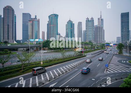 Un plan large montre plusieurs gratte-ciel en verre de grande hauteur en arrière-plan sous un ciel gris clair, certains avec des reflets bleu-vert et des flèches pointues. Au milieugro Banque D'Images