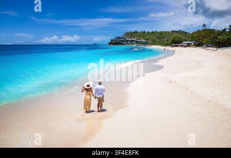Vue élevée d'un couple descendant la belle plage de Darkwood avec une mer turquoise dans les Caraïbes, îles d'Antigua et Barbuda Banque D'Images