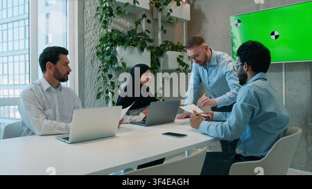 Équipe d'affaires multiethnique discutant des documents, présentation, réunion de bureau, leader, employés d'entreprise, hommes d'affaires, musulmane en hijab, femme d'affaires Banque D'Images