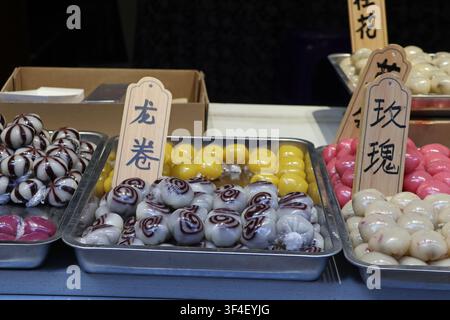 saveurs Rose et Dragon Roll de gâteaux de riz gluant traditionnels chinois exposés avec indication de saveur sur tableau dans un marché de rue à Zhangjiajie Banque D'Images