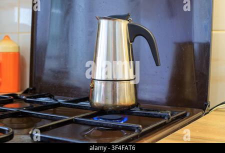 Préparation du café dans une moka. La moka en acier inoxydable repose sur une cuisinière à gaz allumée avec une flamme bleue. L'espresso traditionnel dans une moka est préparé dans le k Banque D'Images