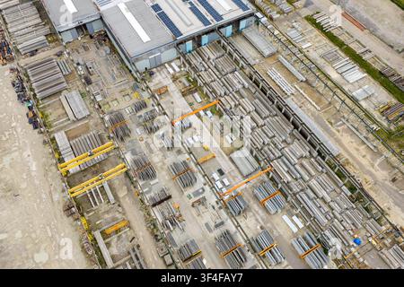 Vue aérienne d'une cour d'usine présentant des rangées d'éléments en béton précontraint, des bâtiments industriels et des grues surdimensionnées en Pologne. Banque D'Images