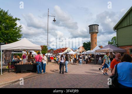 Kuldiga, Lettonie - 25 juillet 2026 : Marché du Festival de la Vieille Ville avec tour d'eau historique et foules en été Banque D'Images