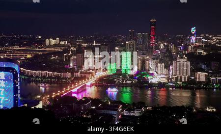 LIUZHOU, CHINE - 10 JUIN 2024 : Une vue aérienne nocturne montrant des gratte-ciel colorés illuminés et un pont lumineux le long de la rivière à Liuzhou, en Chine Banque D'Images