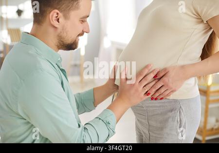 Père joyeux touchant le ventre enceinte de sa femme, couple heureux profitant d'un moment tendre avec le bébé à naître. Banque D'Images