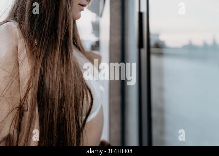 Femme aux cheveux debout sur un balcon surplombant une ligne d'horizon floue de la ville au crépuscule avec beaucoup d'espace pour le texte Banque D'Images