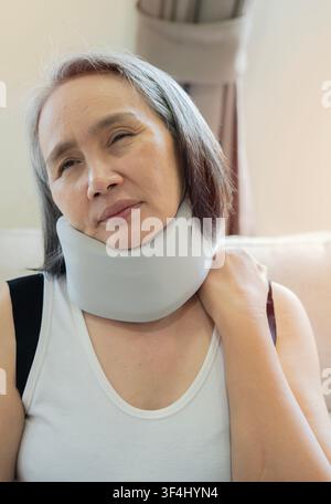 Femme asiatique mature avec un col cervical sur le cou souffrant de douleurs à la maison, se remettant d'un accident physique et d'une blessure. Concept de soins de santé. Banque D'Images