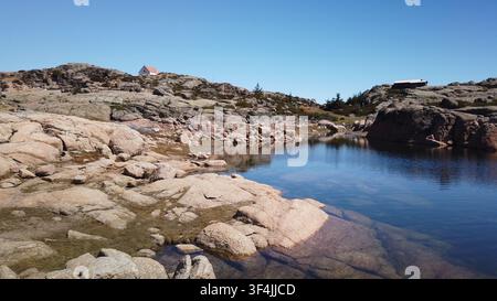 Une vue panoramique d'un lac clair et calme entouré de roches de granit escarpées et d'une végétation clairsemée dans le terrain montagneux de la Serra da Estrela Banque D'Images