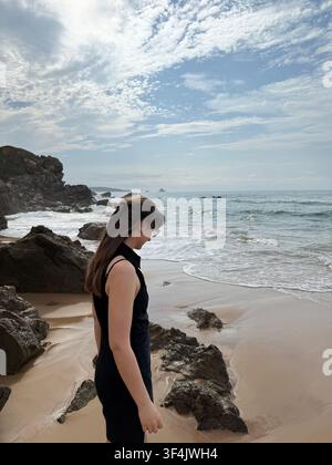 Femme debout parmi des rochers sur une petite plage de l'Atlantique le long de la Costa Quebrada en Cantabrie, Espagne. Banque D'Images