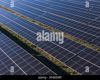 Une vue aérienne montre de grandes panneaux solaires générant de l'électricité propre dans un paysage rural avec des champs verts. Banque D'Images