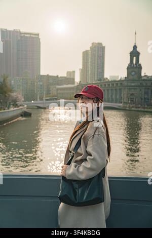 Voyageuse portant une casquette marron regarde par-dessus son épaule près d'une tour d'horloge historique, pont de Zhapu, Shanghai Banque D'Images