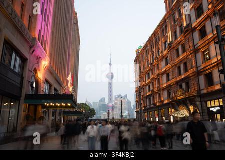 Des bâtiments éclairés au néon encadrent la rue piétonne animée de Nanjing Road au crépuscule, Shanghai, Chine Banque D'Images