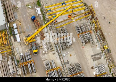 Vue aérienne de la production d'éléments en béton précontraint avec une grue mobile soulevant des matériaux de construction dans une cour d'usine en Pologne. Banque D'Images