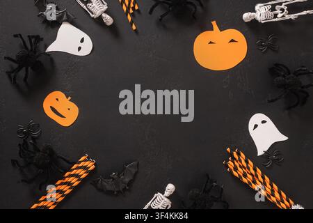 Cadre plat Halloween composé de fantômes, squelettes, araignées, chauves-souris et décorations saisonnières sur fond noir avec espace libre. Vue par-dessus. Banque D'Images