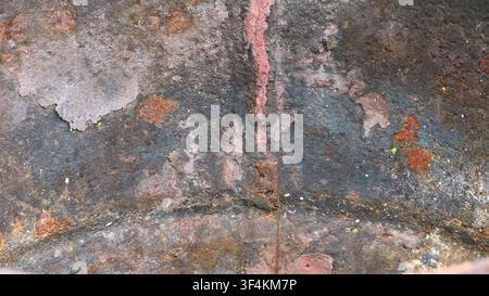 Vue macro d'une surface métallique vieille et fortement rouillée. La texture est rugueuse et grossière, avec des couches d'écailles effritées. Couleurs gris foncé, brun, rouge Banque D'Images