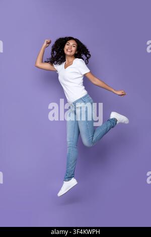 Happy Mexican Lady Jumping posant en studio, vertical Shot Banque D'Images