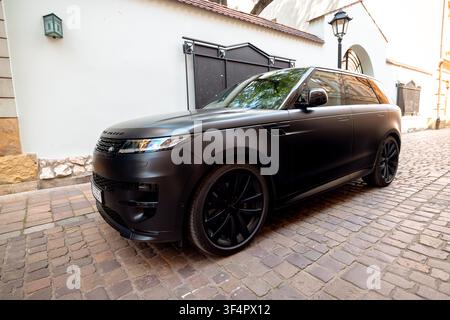 Range Rover Sport noir mat posé sur une rue pavée à Cracovie, Pologne. Banque D'Images