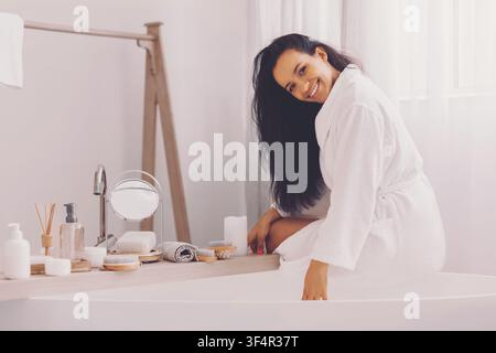 Jeune femme heureuse se détendant en peignoir dans la salle de bain à la maison, concept de routine de soins de la peau Banque D'Images