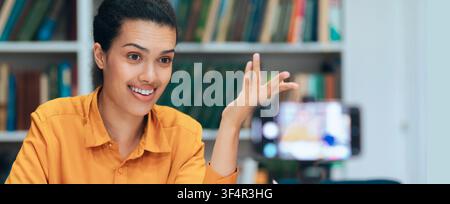Jeune femme latino-américaine souriante interagissant avec le public au bureau, concept commercial Banque D'Images
