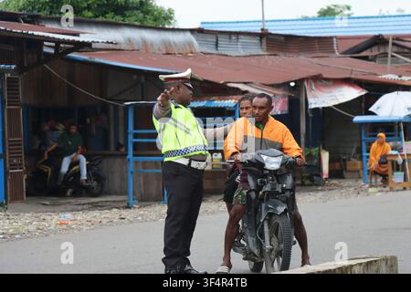 Un officier de police routière indonésien arrête un motocycliste papou circulant sans casque sur une rue à Papua, en Indonésie. Banque D'Images