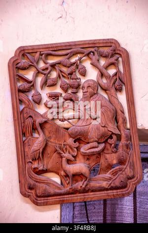 Institut Norbulingka, Sidhpur, Himachal Pradesh, Inde. Dans un atelier, une sculpture sur bois détaillée représentant un homme âgé assis, entouré d’un cerf Banque D'Images