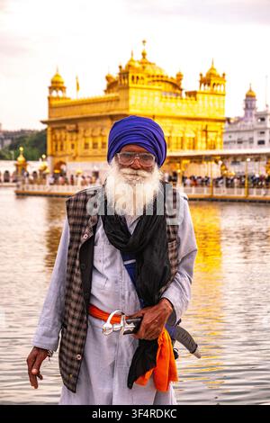 Un homme sikh, portant un turban bleu et une barbe blanche, se tient devant le Temple d'Or à Amritsar, en Inde Banque D'Images