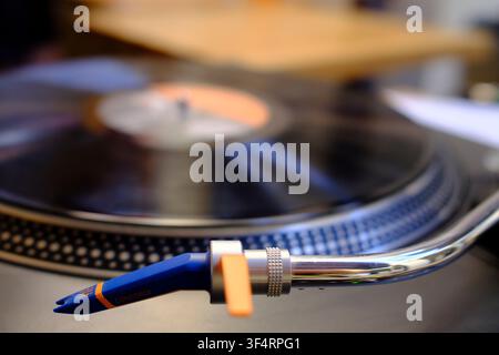 Grossissement d'une cartouche Concorde bleue et orange montée sur le bras tonal d'un tourne-disque ; un disque noir en rotation est visible en arrière-plan flou. Banque D'Images